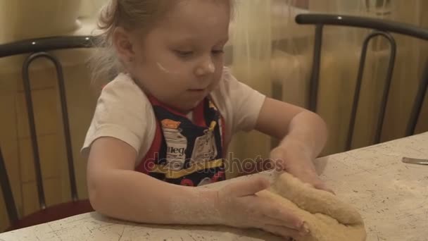 Девочка на столе Китчен, тесто на коленях — стоковое видео