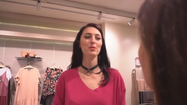 Mooie meisjes vriendinnen in winkel kiezen kleren — Stockvideo