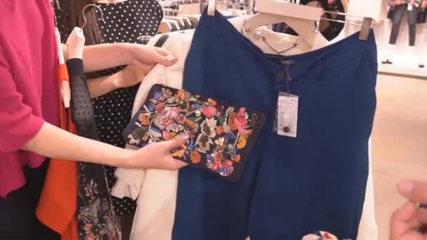 Mooie meisjes vriendinnen in winkel kiezen kleren — Stockvideo