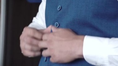 Bir erkek yeleğinin düğmelerini ilikler