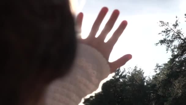 Dívka ruka se snaží zachytit paprsky slunce — Stock video