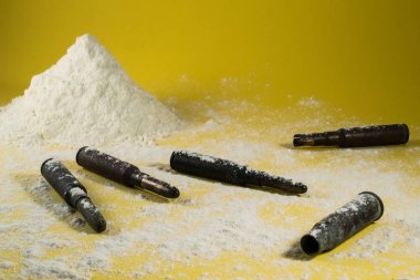 Cocaine drug with bullets in a yellow background clipart