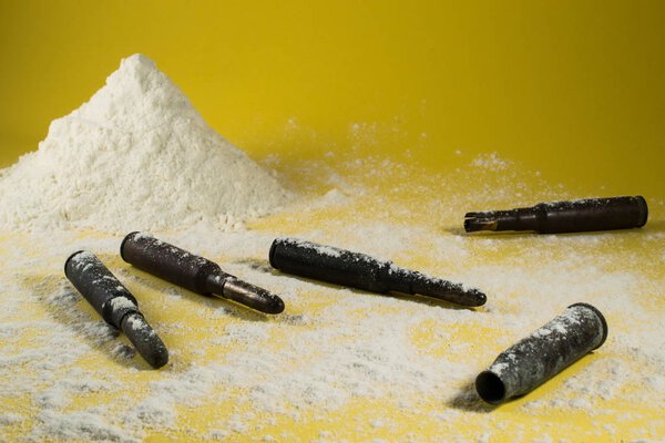 Cocaine drug with bullets in a yellow background