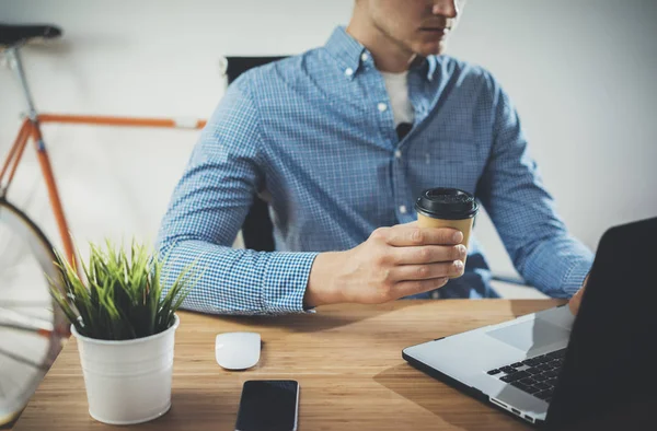 Freelancer usando laptop y sosteniendo café — Foto de Stock