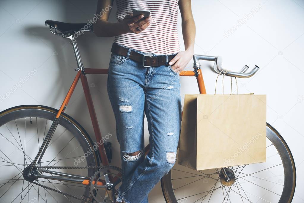 girl with bicycle using modern smartphone