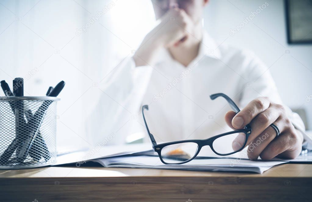 businessman at his office holding glasses