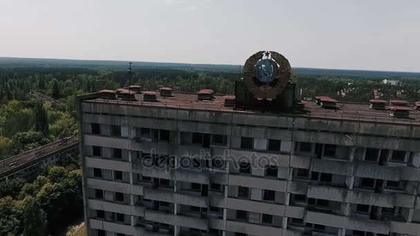 Bâtiment à plusieurs étages abandonné avec les armoiries soviétiques sur la façade dans la ville morte de Pripyat. Ville fantôme dans la zone de Tchernobyl . — Video