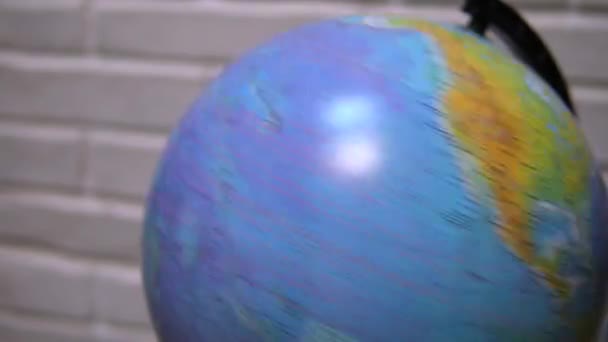 Un uomo che gira un globo e lo punta. L'uomo che sceglie il suo prossimo viaggio su un globo rotante . — Video Stock