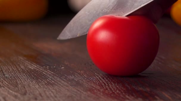 Tomate cortando primer plano. Cuchillo de cocina cortando tomate fresco en tabla de cortar de madera . — Vídeos de Stock