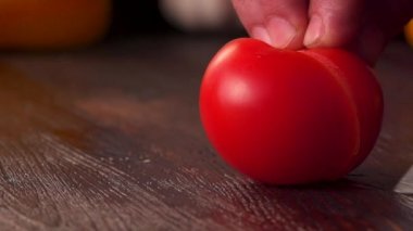 Mutfak bıçağı kullanarak, tahta kesme tahtasıyla taze domates keserek ellerini kapat. Domates kesimi yakın plan. Yavaş çekim.