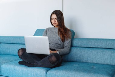 kanepe ve beyaz duvar üstünde laptop ile kız