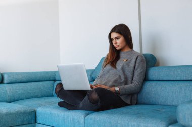 kanepe ve beyaz duvar üstünde laptop ile kız