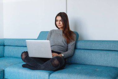 kanepe ve beyaz duvar üstünde laptop ile kız