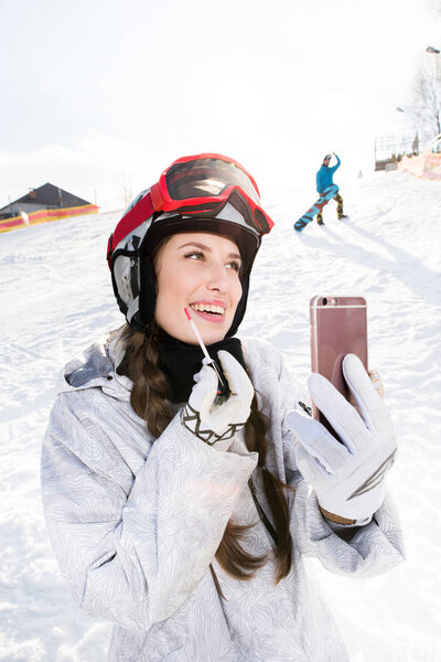 Female snowboarder applying lip gloss
