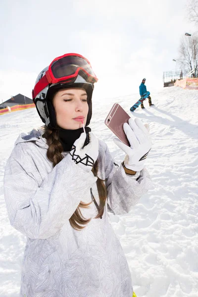 Female snowboarder applying lip gloss — Stock Photo