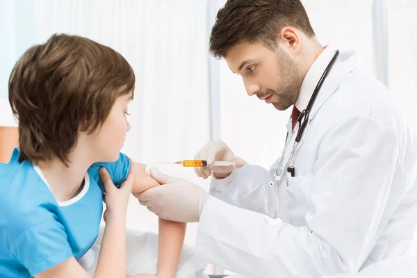 Médico haciendo inyección a niño - foto de stock