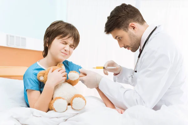 Médico haciendo inyección a niño - foto de stock