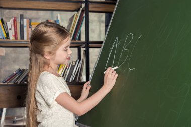 Girl writing on chalkboard 