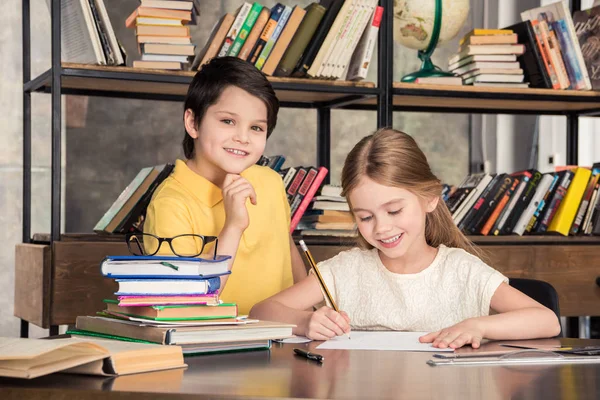 Crianças em idade escolar estudando na biblioteca — Fotografia de Stock