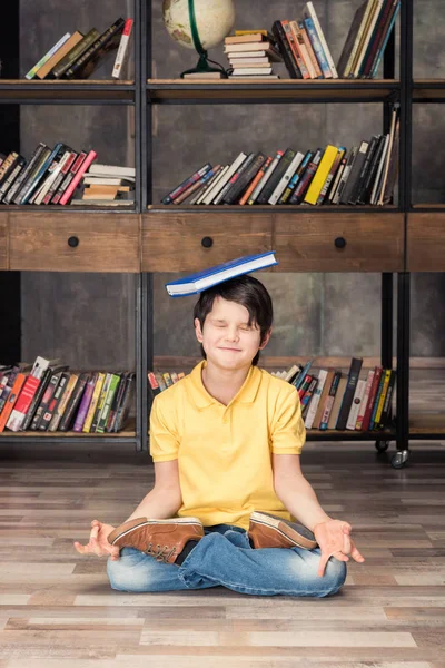 Jongen met boek in bibliotheek — Stockfoto