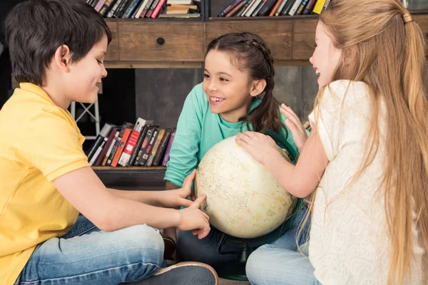 Kinderen met globe in bibliotheek — Stockfoto