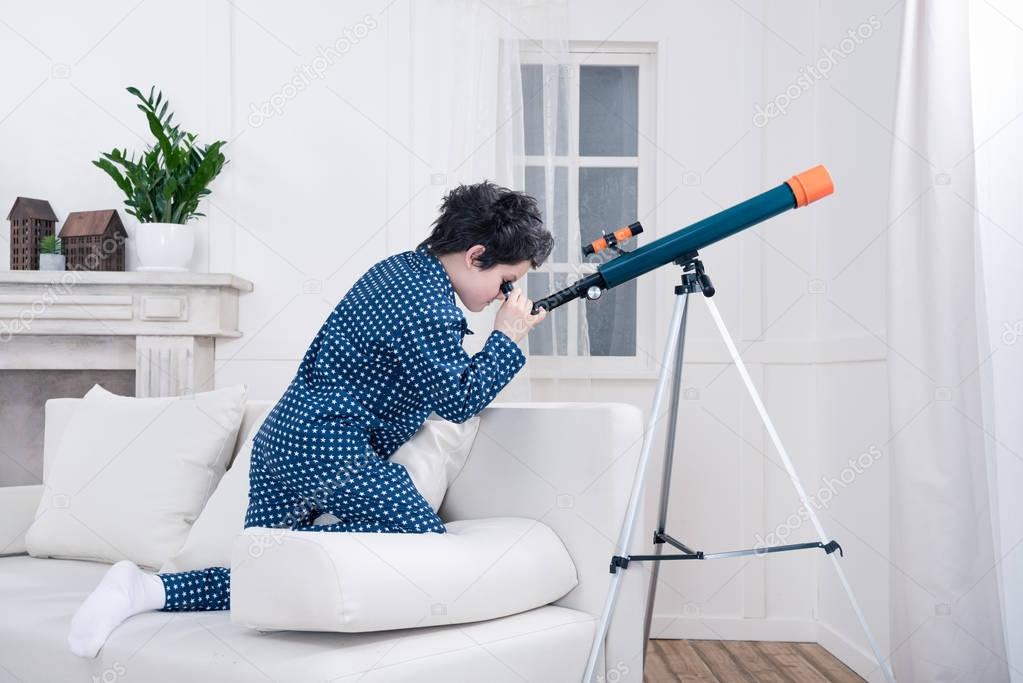 little boy looking through telescope