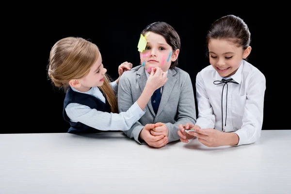 Girls putting notes on boy's face — Stock Photo, Image