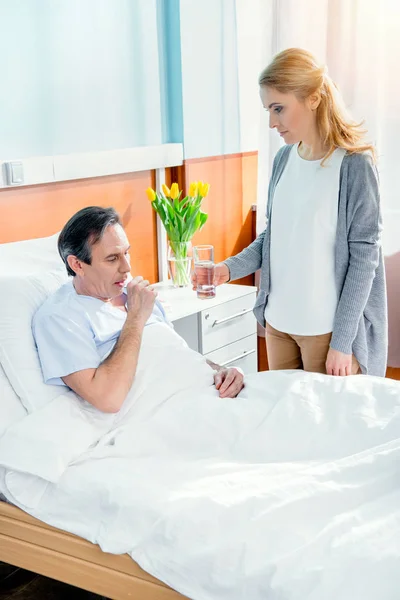 Wife giving glass of water to husband — Stock Photo, Image