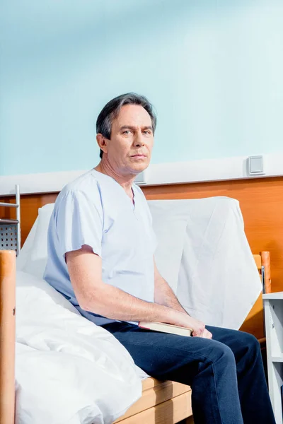 Чоловік сидить на лікарняному ліжку — стокове фото