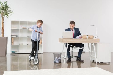 boy riding skooter at office clipart