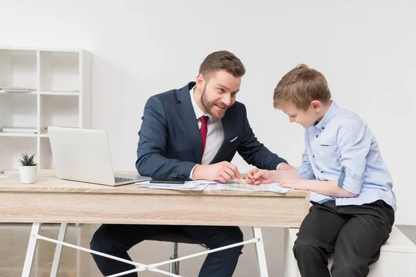 Zakenman met zoon puttend uit handelspapieren — Stockfoto