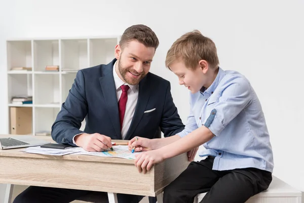 Бизнесмен рисует на деловых бумагах с сыном — стоковое фото