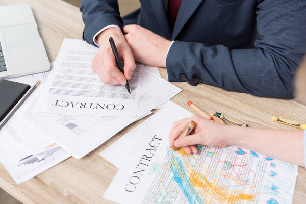 Бизнесмен рисует на деловых бумагах с сыном
