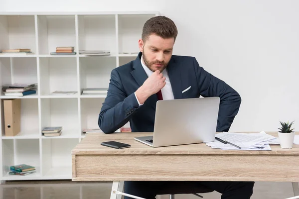 Självsäker affärsman vid bord i office — Stockfoto