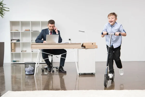 Rapaz feliz montando skooter no escritório — Fotografia de Stock