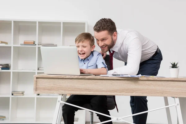 Businessman playing on laptop with son — Stock Photo, Image