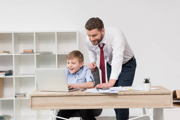 Businessman playing on laptop with son