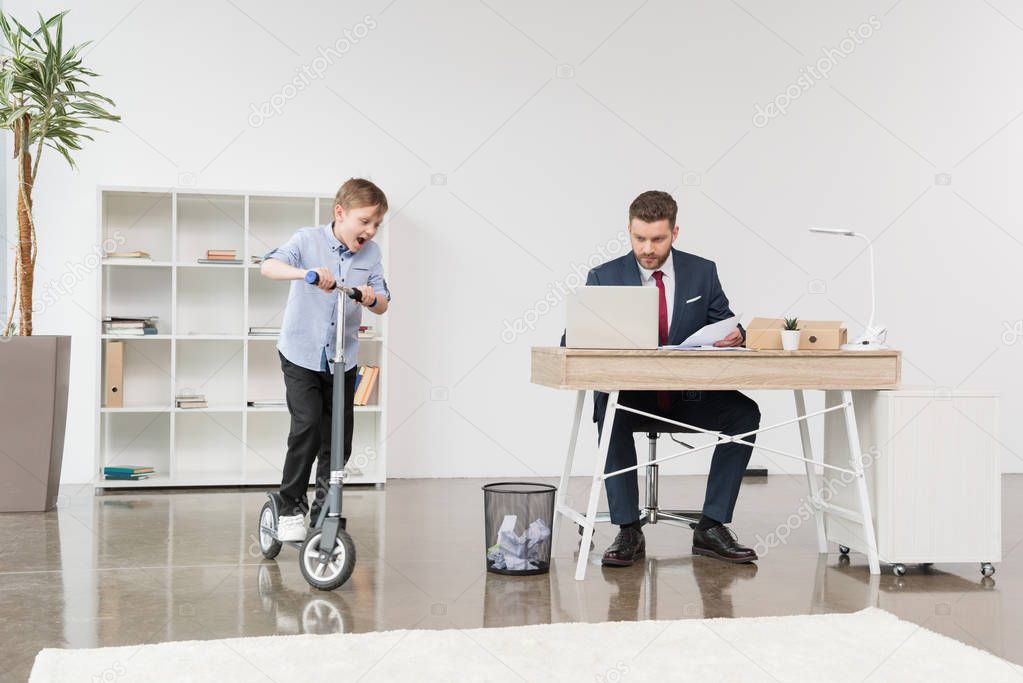 boy riding skooter at office