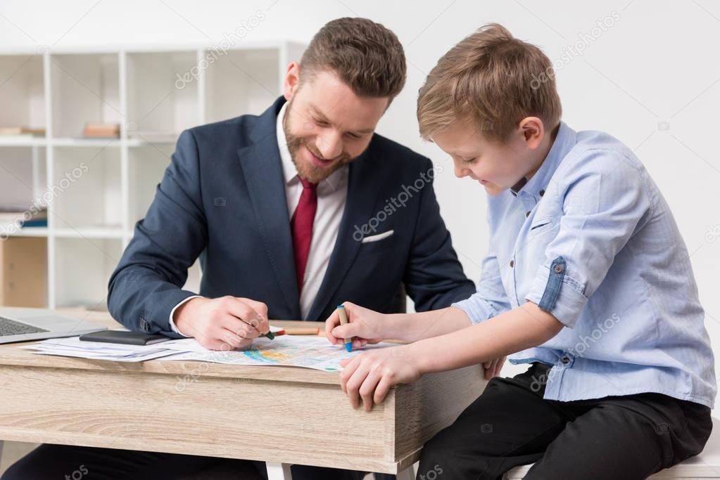 Businessman drawing on business papers with son