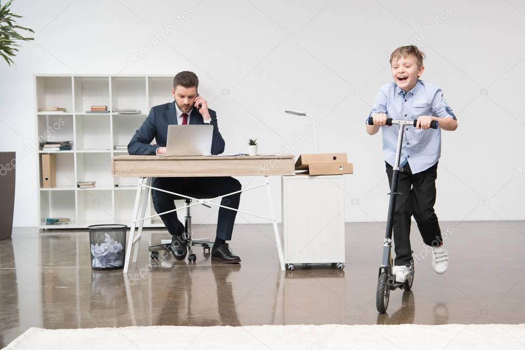 Happy boy riding skooter at office