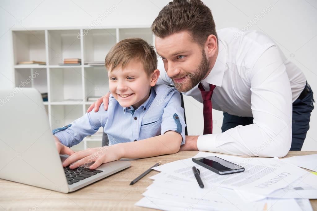 Businessman playing on laptop with son
