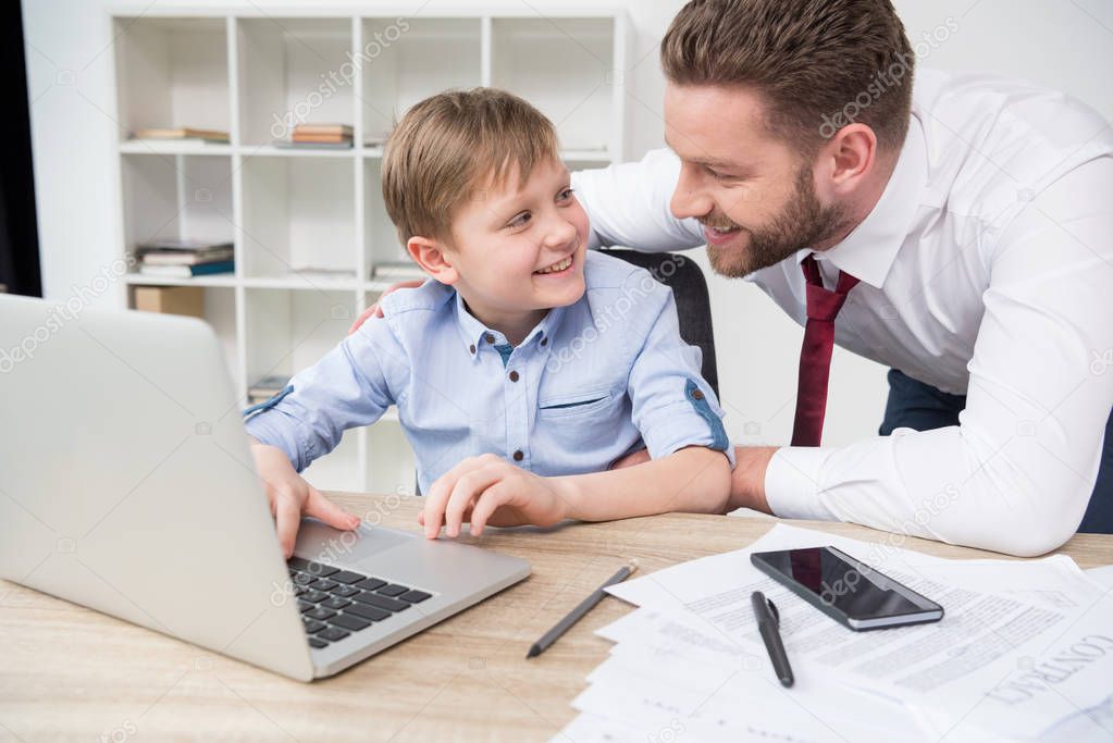 Businessman playing on laptop with son