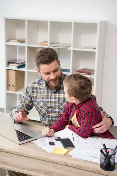 Freelancer trabajando en la mesa con su hijo — Foto de Stock