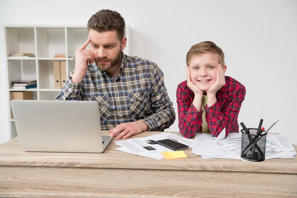 Freelancer trabajando en la mesa con su hijo — Foto de Stock