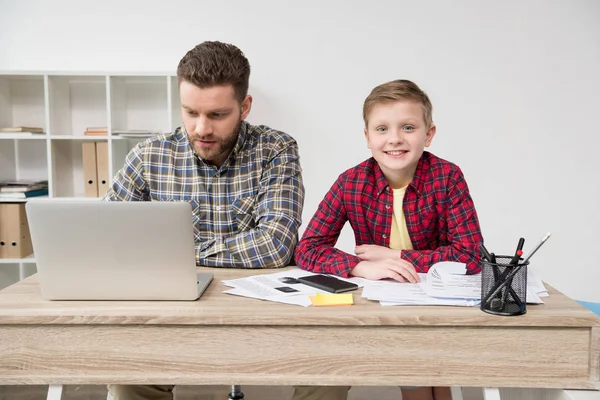 Freelancer trabajando en la mesa con su hijo — Foto de Stock