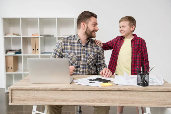 Freelancer trabajando en la mesa con su hijo — Foto de Stock