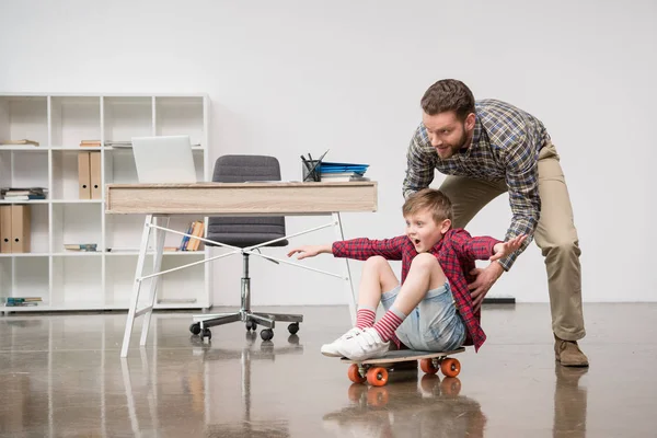 Affärsman med son på skateboard — Stockfoto