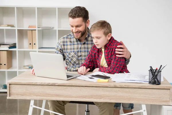 Freiberuflerin arbeitet mit Sohn am Tisch Stockbild