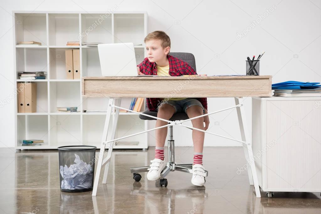 schoolboy using laptop at office