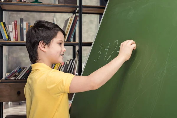 Junge schreibt auf Kreidetafel — Stockfoto